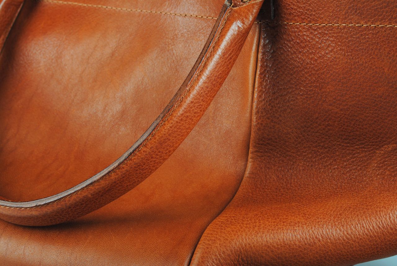 Detail view of a high-quality brown leather bag with smooth texture.