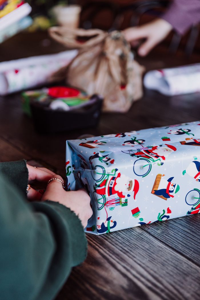 Close-up of Christmas gift being wrapped with festive paper, capturing holiday spirit.