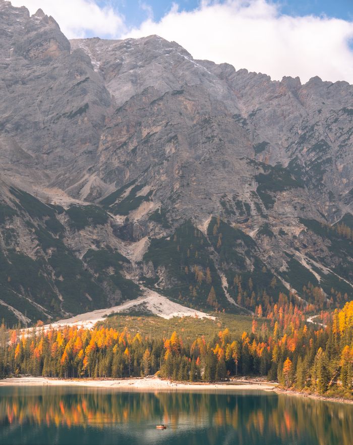 Breathtaking view of the Dolomites in autumn with vibrant foliage reflected in a serene lake.