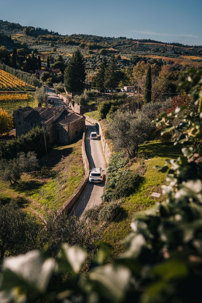 A peaceful drive through Tuscany's picturesque autumn landscape, featuring lush greenery and rustic architecture.
