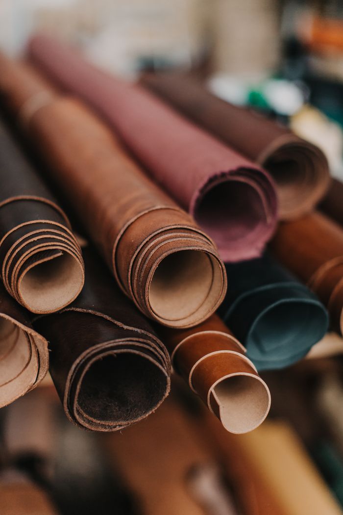 our-services-02 Close-up of various colored leather rolls in a workshop, featuring texture and vibrant hues.