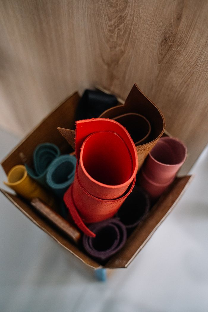 our-services-04 An assortment of colorful rolled leather pieces stored in a cardboard box.